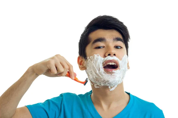 Jovem bonito cara com espuma em seu rosto abriu a boca e rapa sua máquina de barba close-up — Fotografia de Stock