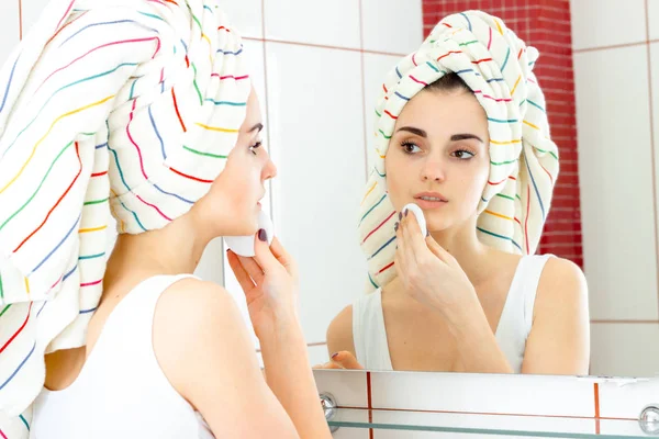 Mooi meisje met handdoek op hoofd wegspoelt make-up — Stockfoto