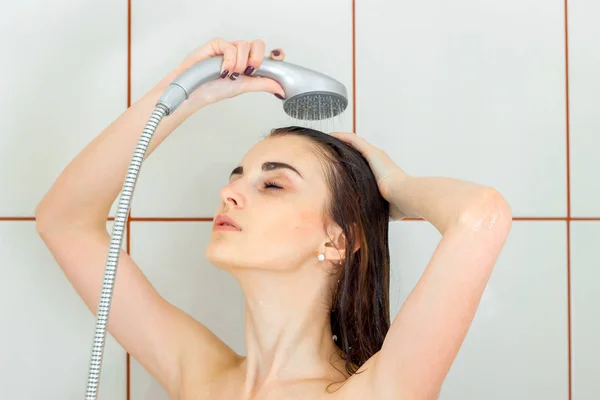 Beautiful young brunette washes her hair in the shower — Stockfoto