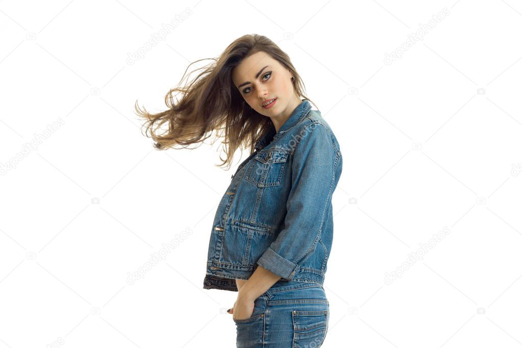 charming young girl in jeans jacket looks straight and her hair fly through the air