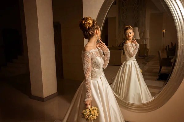 Hinreißende junge blonde Braut schaut in den Spiegel — Stockfoto