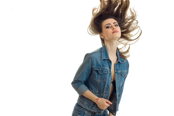 Молодая красивая девушка в джинсовой куртке стоит перед камерой и ее волосы летят по воздуху — стоковое фото