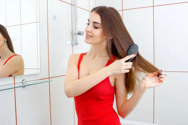 Vrolijke brunette vrouw in rode t-shirt kammen haar — Stockfoto