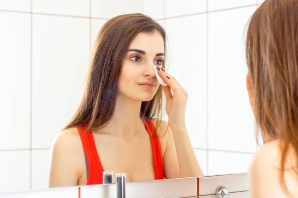 Молодая красивая женщина очищает лицо макияжем — стоковое фото