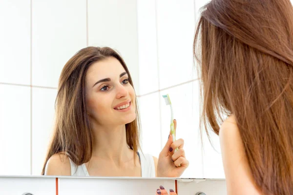 Jovem mulher bonita escovando os dentes antes de dormir e sorri — Fotografia de Stock