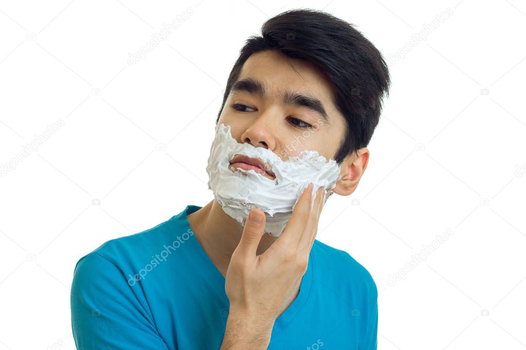 beautiful narcissistic guy looks away and putting a beard foaming close-up