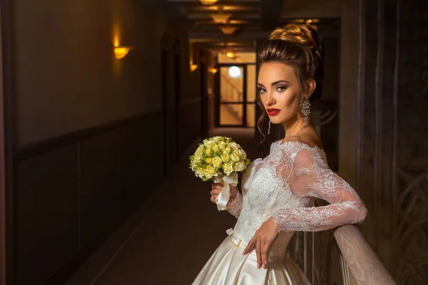 Junge schöne Braut mit einem Strauß Rosen in den Händen — Stockfoto