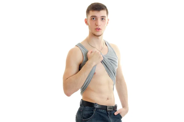 Muskulöser junger Mann zieht sein Hemd aus und blickt in die Kamera — Stockfoto