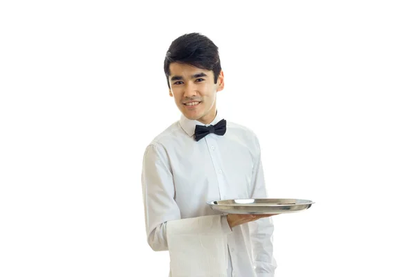 Człowiek wesoły brunetka kelner z srebra tacę w ręce uśmiechając się — Zdjęcie stockowe