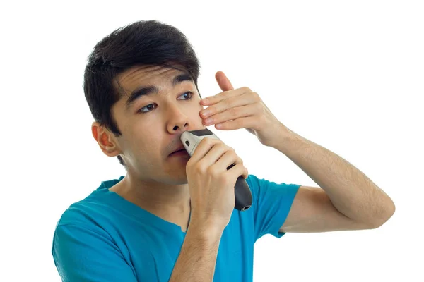 Portrait of young brunette man in blue t-shirt shaving with trimmer — Stock Photo, Image