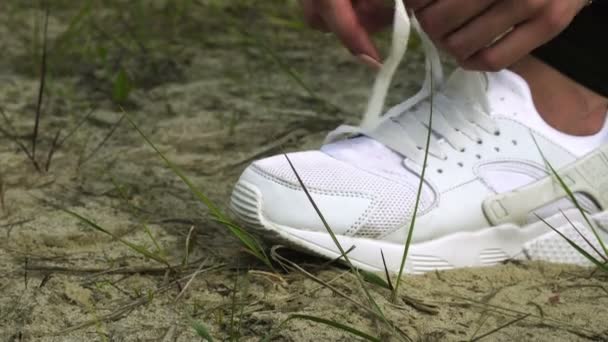 Una mujer ata un cordón de zapato blanco — Vídeo de stock