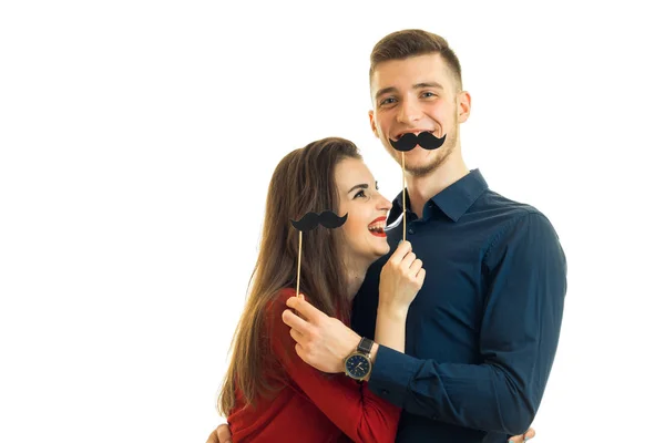 Alegre joven chica y chico son celebración de papel negro bigotes — Foto de Stock