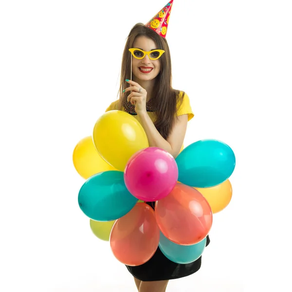 Retrato vertical de una hermosa joven que se para frente a la cámara y sostiene gafas de sol y muchos globos grandes — Foto de Stock