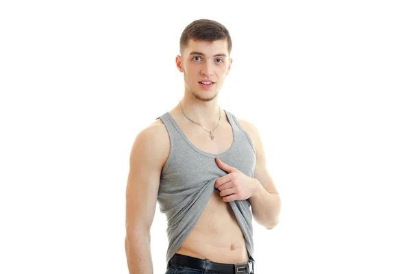 Ung sportig sexig kille plockar upp en t-shirt och tittar på kameran — Stockfoto