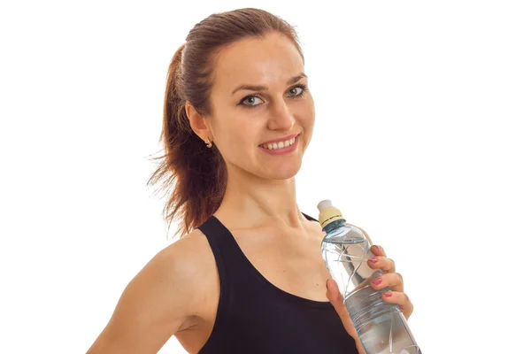 Retrato horizontal de los deportes de niña encantadora que mantiene la botella de agua y sonriendo —  Fotos de Stock