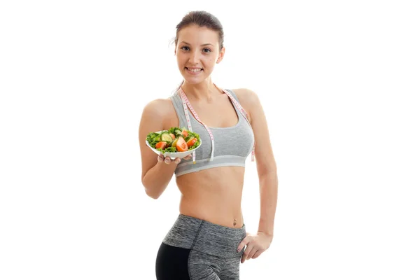 Delgada chica joven atractiva sosteniendo una ensalada de verduras y sonriendo —  Fotos de Stock