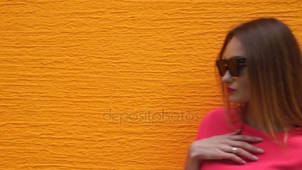 Jonge mooie blonde dame in zonnebrillen en modieuze rood pak de camera kijken — Stockvideo
