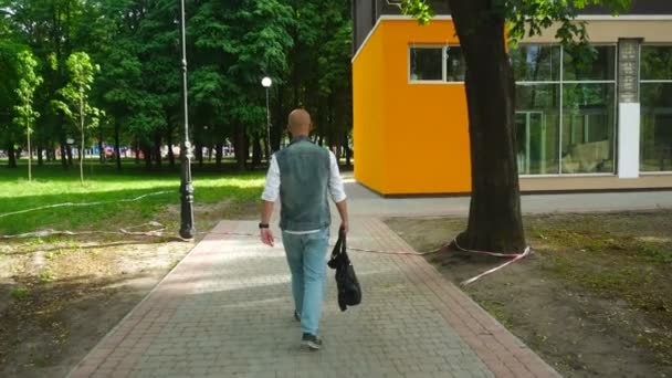 Magnifique jeune homme en jeans vêtements avec sac dans la main marche dans la rue — Video