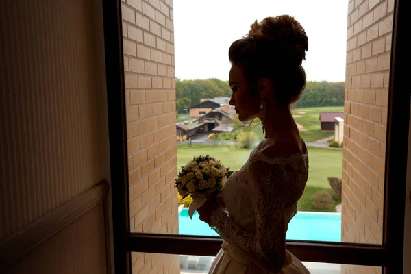 Silhouette der jungen charmanten Braut mit Rosenstrauß — Stockfoto