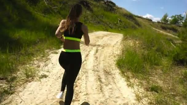 Schlanke junge Frau in Sportuniform läuft herum — Stockvideo