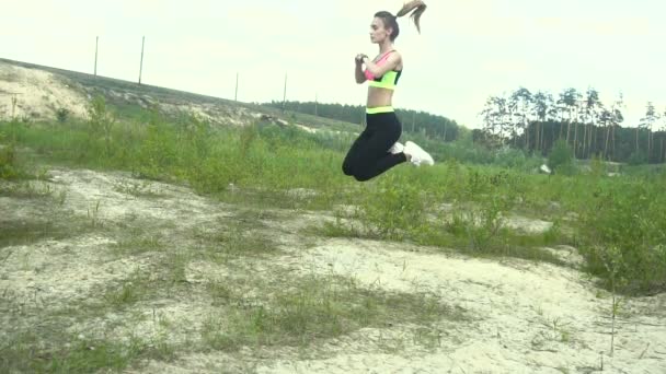 Красивая юная спортивная девушка в форме практикующая прыжки — стоковое видео