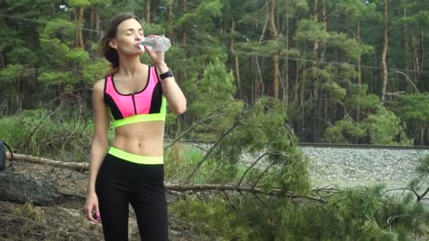 Delgada rubia en uniforme deportivo bebe agua después de un duro entrenamiento — Vídeo de stock