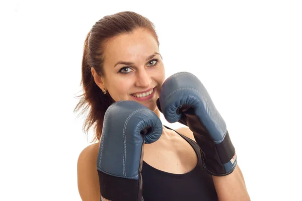 A close-up portrait of young beautiful girl who smiles and holding hands in boxing gloves near the person — Stock Photo, Image