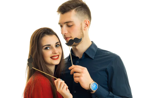 Casal alegre sorrindo e se divertindo com bigode de papel nas mãos — Fotografia de Stock