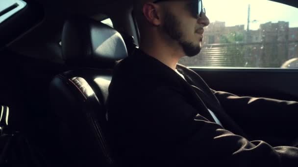 Joven hombre de moda en gafas de sol negras conduciendo un coche — Vídeo de stock