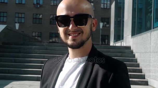 Giovane uomo d'affari alla moda in occhiali da sole sorridente sulla macchina fotografica — Video Stock