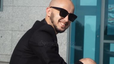 Neşeli genç iş adamı takım elbise ve kameraya gülümseyen güneş gözlüğü