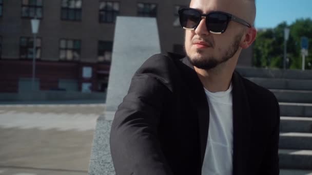 Hombre joven con estilo en traje y gafas de sol negras — Vídeos de Stock