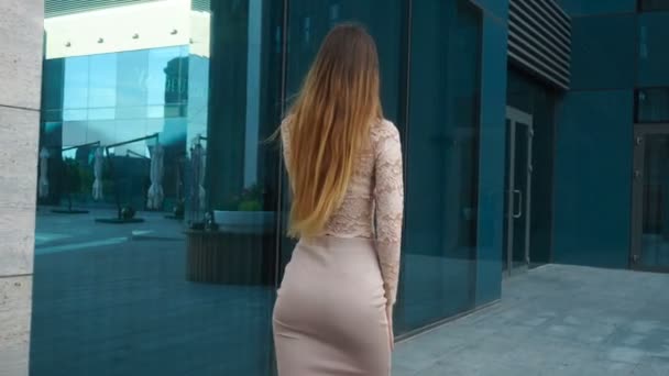 Chica en falda con hermosas nalgas y pelo largo va alrededor de la ciudad y habla en un teléfono móvil — Vídeo de stock