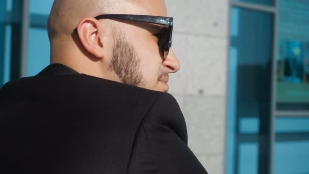 Jeune homme à la mode en lunettes de soleil noires regarde la caméra — Video