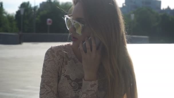 Bonita mujer rubia en gafas de sol hablando en el teléfono móvil — Vídeos de Stock