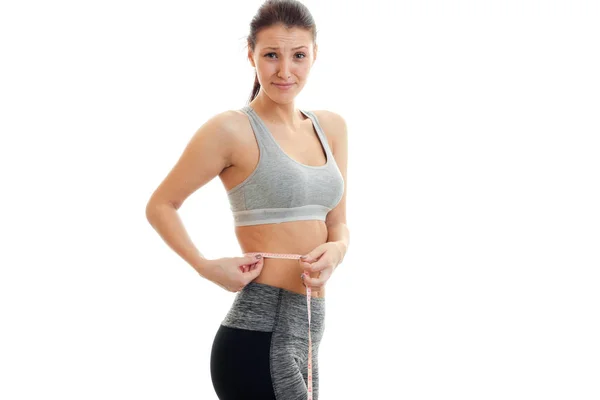 Athletic young athletic girl takes the waist and smiling — Stock Photo, Image