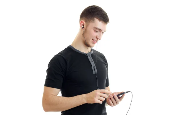 Portrait of a young handsome guy in a t-shirt with a phone in hands — Stock Photo, Image
