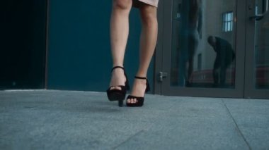 yüksek topuklar üzerinde genç iş kadını sokakta ve cep telefonu üzerinde konuşurken içeri girer