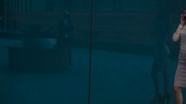 Seksi ince iş kadını üstünde hareket eden telefon görüşmeleri ve yan yan yürüyor