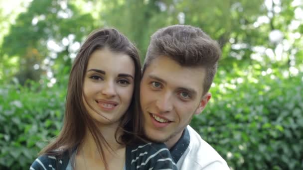 Красивая молодая влюбленная пара смотрит и улыбается на камеру на улице — стоковое видео