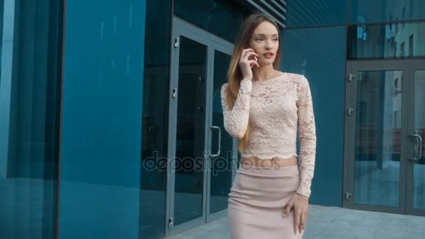 Divatos barna ruhás hölgy szőke üzleti sétál az utcán, és beszél a mobiltelefon — Stock videók