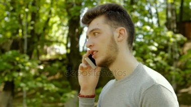 genç yakışıklı adam parkta cep telefonu konuşurken