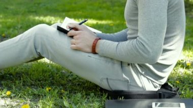 çim ve şöyle bir not defterindeki bir parkta oturan adam