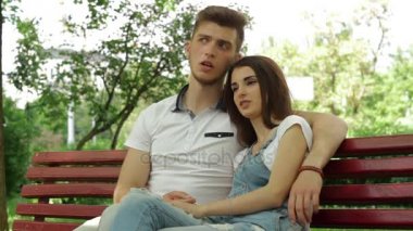 bir adamla bir kız sarılma ve parkta bir bankta konuşuyor