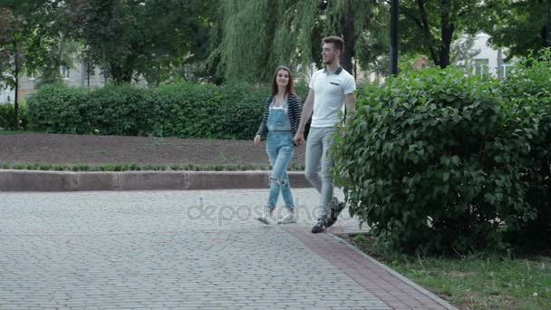 Joven pareja enamorada camina en el parque y se toman de la mano — Vídeos de Stock
