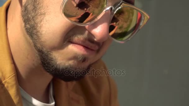 Модный молодой человек в золотых солнечных очках на открытом воздухе — стоковое видео