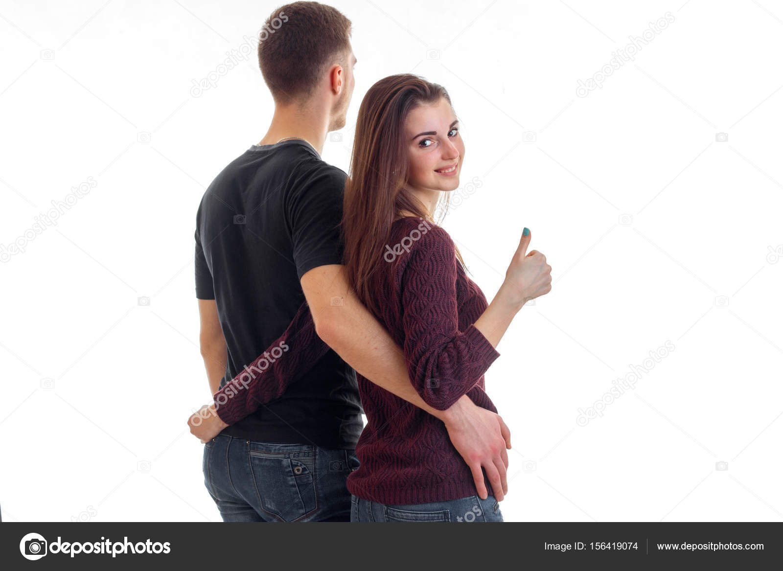 Young couple hugging waist and girl showing thumbs up Stock Photo
