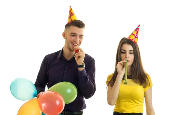 Casal feliz soprando em chifres e rindo — Fotografia de Stock