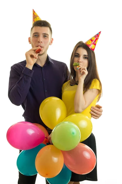 Retrato vertical de alegre jovem casal soprando chifres em uma festa de aniversário — Fotografia de Stock