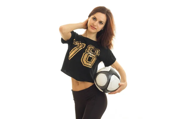 Schlanke Sportlerin steht im Studio und hält einen Fußballball in der Hand — Stockfoto